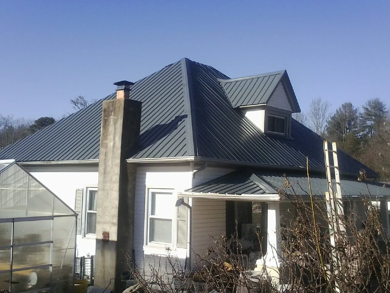 Dark blue standing seam metal roof on a white farmhouse with dormer — Slate & Tile Roof Repair by Roofing Brothers in Gilbertsville