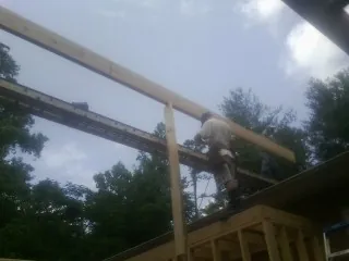 Carpenter setting a ridge beam over a new addition frame — Ice Dam Removal by Roofing Brothers in Gilbertsville