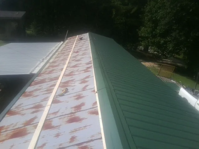 Old rusted panels beside newly installed green metal roofing — Wind Damage Roof Repair by Roofing Brothers in Gilbertsville