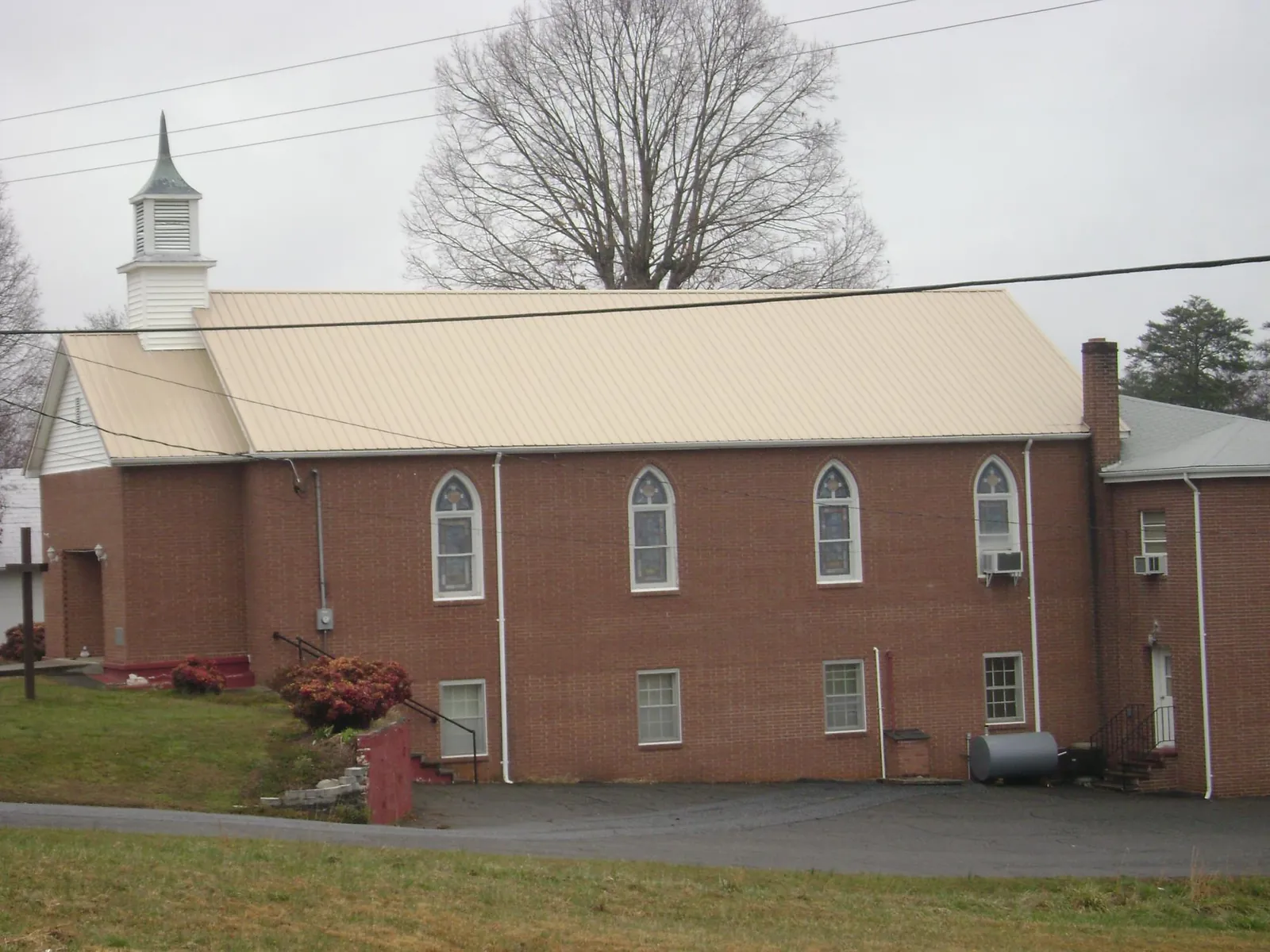New tan metal roof on a brick church with a white steeple in Gilbertsville